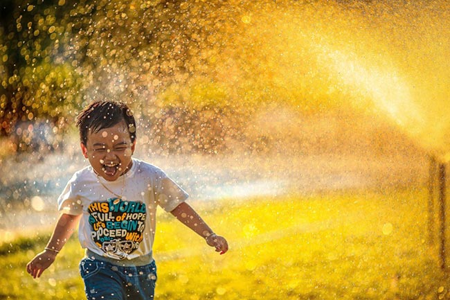 boy running through sprinkler